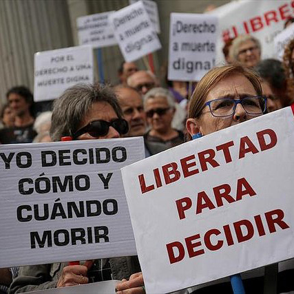 Activistas de DMD se manifiestan frente al Congreso de los diputados con un cartel que lee 'Yo decido cómo y cuándo morir' y otro que dice 'Libertad para decidir'